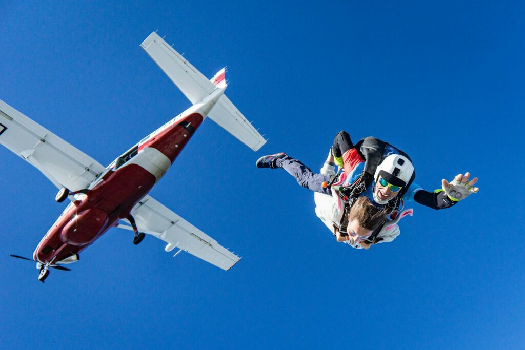 Skydivers falling from a small plane during a tandem jump.
